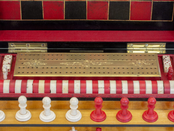 Close up of the top of the box showing the chess pieces, draughts counters and the cribbage board